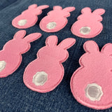 six fuzzy pink bunny patches on a denim background