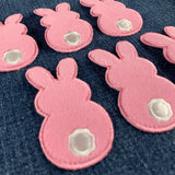 six fuzzy pink bunny patches on a denim background