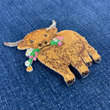 a highland cow embroidered patch displayed on a denim background