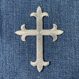 Decorative gray cross on a blue denim background