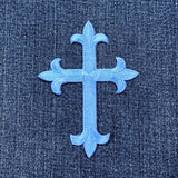 Decorative blue cross patch on a denim background