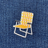 Embroidered patch of a yellow and white chair on denim fabric