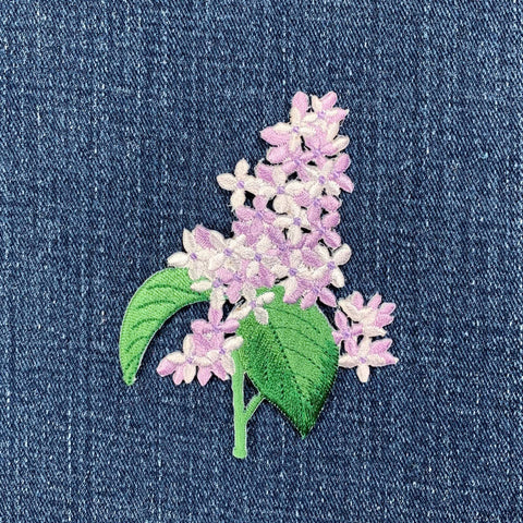 Floral patch with purple flowers and green leaves on denim fabric