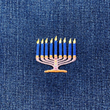 Embroidered menorah patch with candles on a denim background