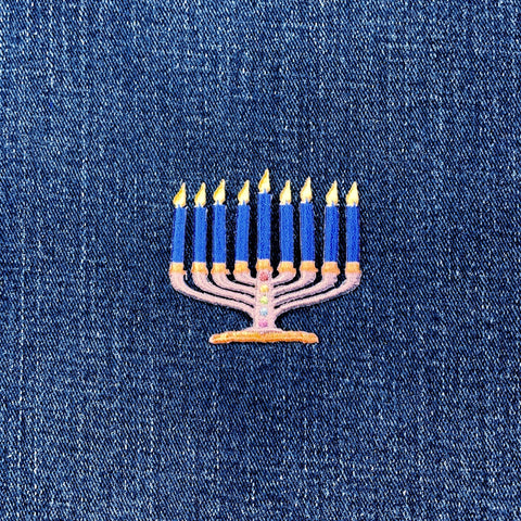 Embroidered menorah patch with candles on a denim background
