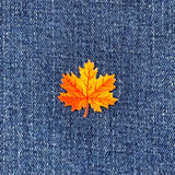 Orange maple leaf patch on a blue denim background