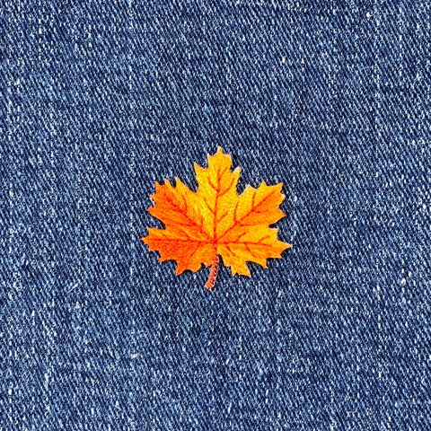 Orange maple leaf patch on a blue denim background