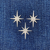 Three silver star-shaped patches on a blue denim background