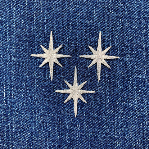 Three silver star-shaped patches on a blue denim background