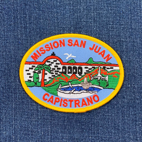 Embroidered patch of Mission San Juan Capistrano on a blue denim background