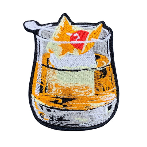 An embroidered patch of a whiskey old fashioned cocktail, on a white background.