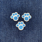 Three blue paw print patches on a denim background