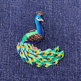 Embroidered peacock patch on denim fabric