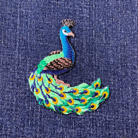 Embroidered peacock patch on denim fabric
