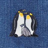 Embroidered patch of penguins on a denim background