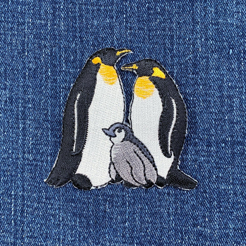 Embroidered patch of penguins on a denim background