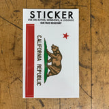 A sticker with the California flag design, including a grizzly bear and a star, on a wooden surface.