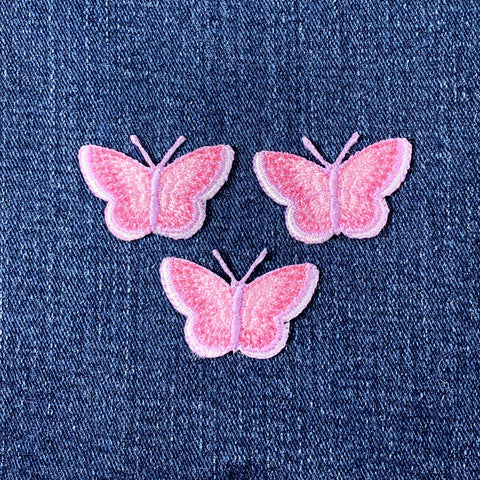 Three pink butterfly patches on a denim background
