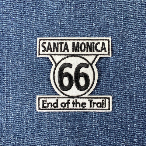 Embroidered patch with the text 'Santa Monica 66 End of the Trail' and the number 66 in a circular design, a sign found on Route 66 in California.