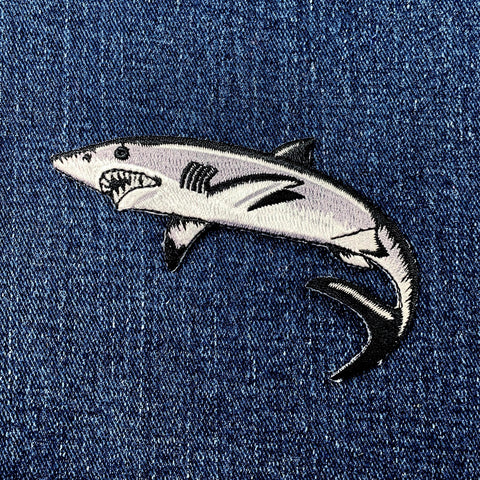 a gray, black, and white shark patch on a denim background