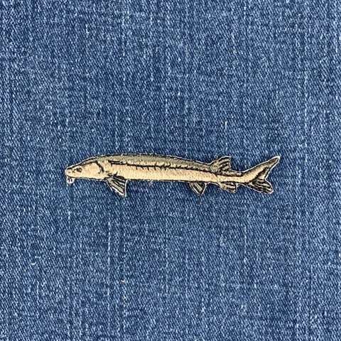 embroidered sturgeon fish patch on a denim background
