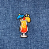 Patch of a tropical drink with an umbrella and cherry on denim fabric