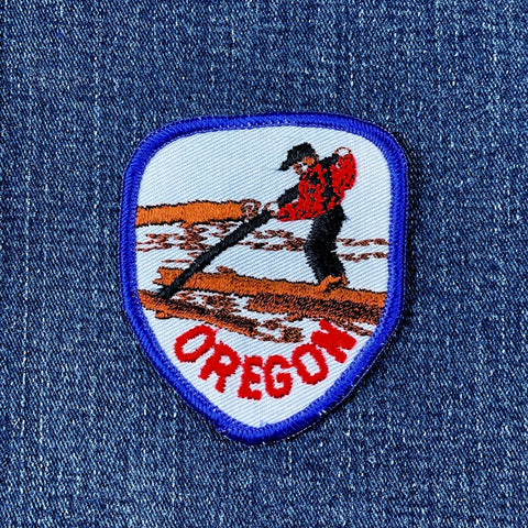 Embroidered patch of a logger with 'Oregon' text on denim fabric