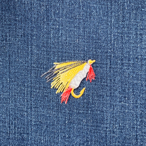 Colorful fly fishing lure patch on denim fabric