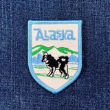 Embroidered patch with 'Alaska' text and dog illustration on blue denim background