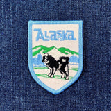 Embroidered patch with 'Alaska' text and dog illustration on denim fabric