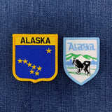 Two Alaska-themed patches on a blue denim background