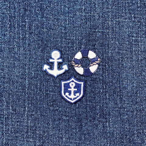 3 Embroidered nautical design patches on denim fabric with an anchor, life buoy, and shield.