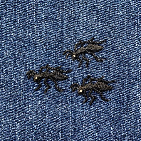 Three black ant-shaped patches on a blue denim background