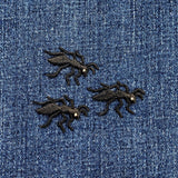 Three black embroidered ant patches on a blue denim fabric background