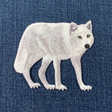 White embroidered wolf patch on blue denim fabric