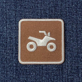 A square embroidered patch featuring a white ATV icon on a brown background, bordered in white and placed on a blue denim fabric.