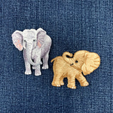 Two embroidered elephant patches on a denim background