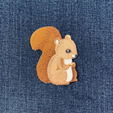 Embroidered squirrel patch on denim fabric