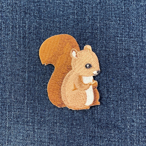 Embroidered squirrel patch on denim fabric