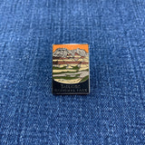 Pin with a mountain landscape featuring a Badlands National Park theme on a blue denim background