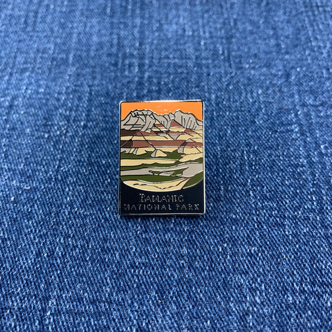 Pin with a mountain landscape featuring a Badlands National Park theme on a blue denim background