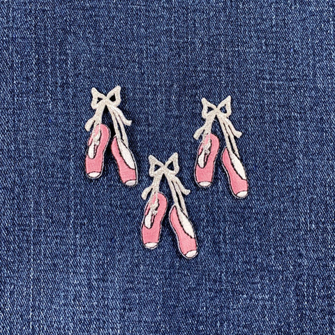 Embroidered pink ballet shoe patches on a denim background