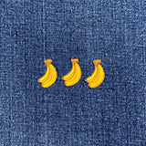 3 mini embroidered bananas patches in a row on a denim background