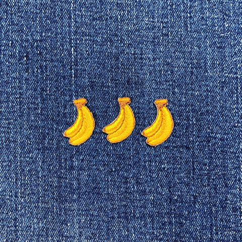 3 mini embroidered bananas patches in a row on a denim background