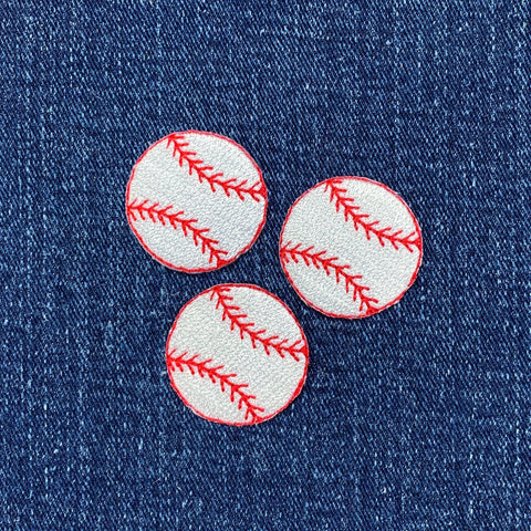 Three baseball-shaped patches with red stitching on a denim background