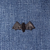 Black bat-shaped patch on blue denim fabric