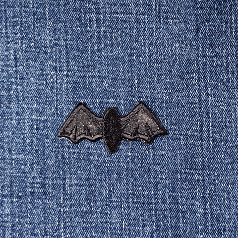 Black bat-shaped patch on blue denim fabric