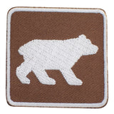 An embroidered square patch featuring a white bear silhouette on a brown textured background, finished with a white border.