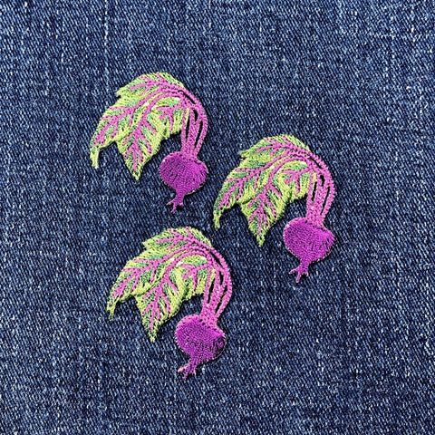 Three embroidered beet patches on denim fabric.