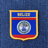 Embroidered patch with 'BELIZE' text on a blue background with red and yellow border, on a denim fabric.